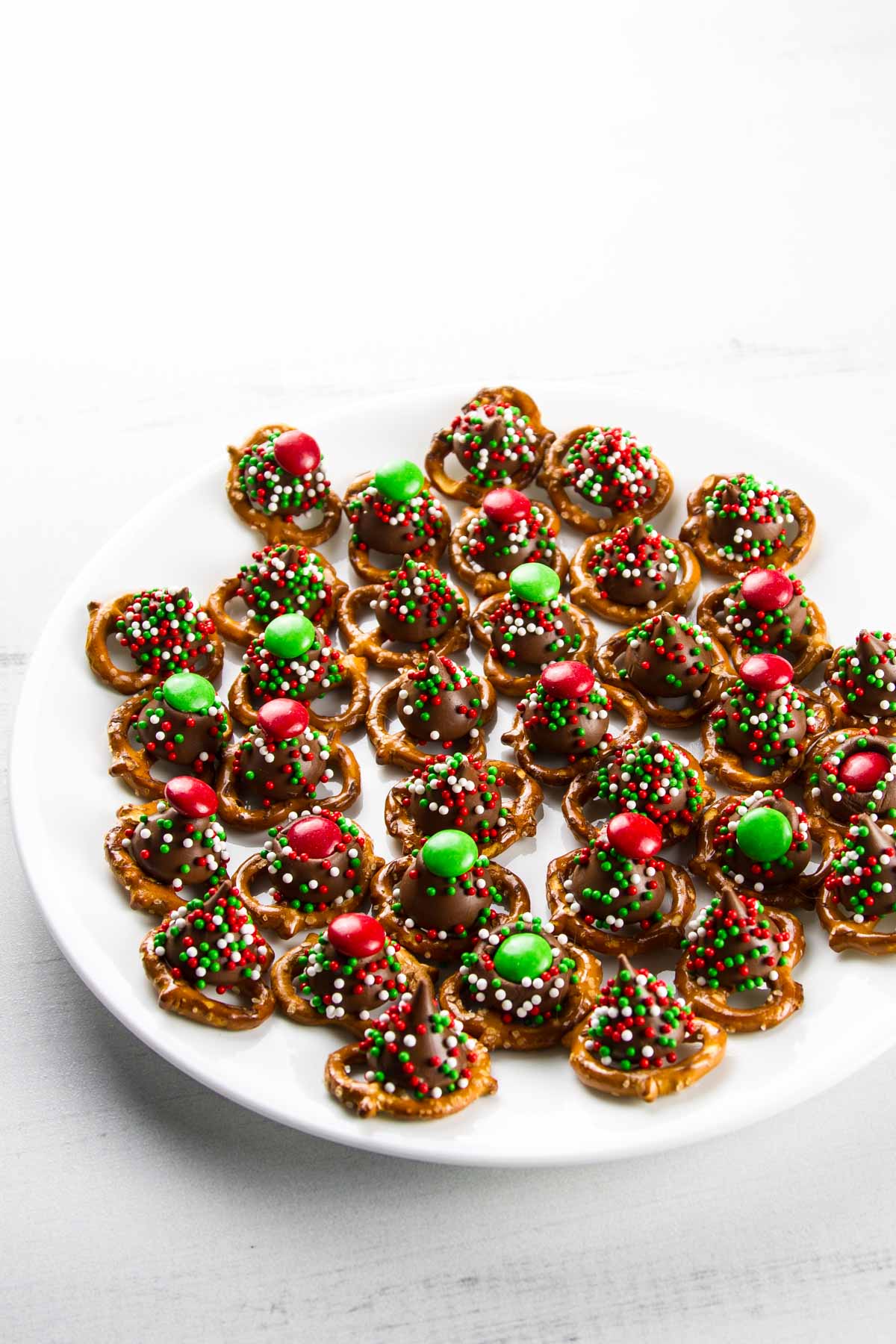 a white plate filled with christmas m&m pretzel hugs