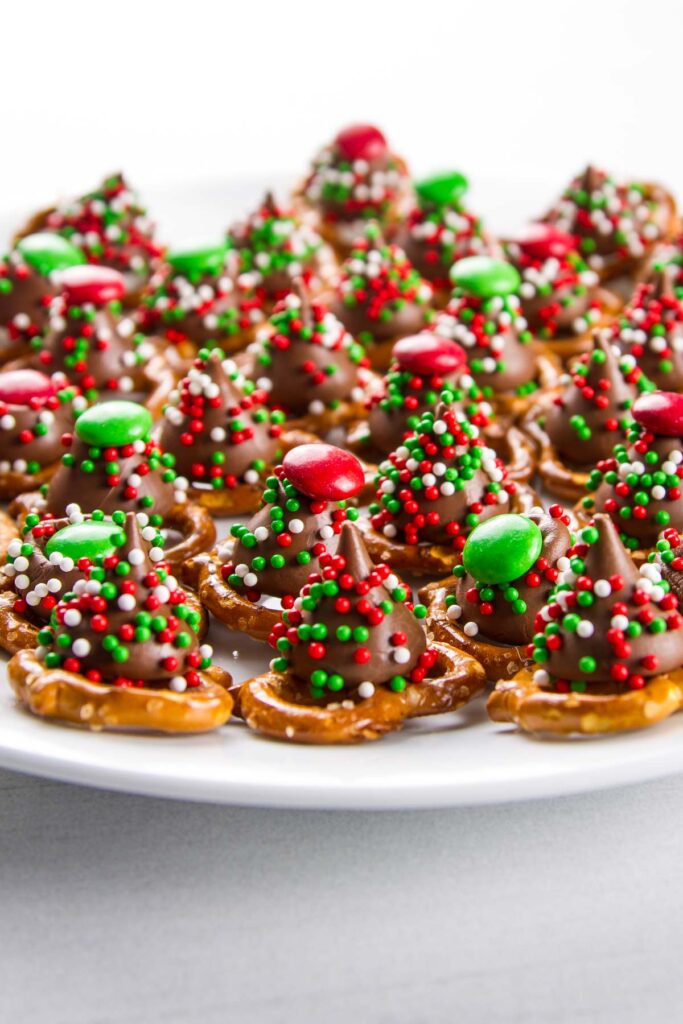 a side view of a cookie plate filled with christmas m&m pretzel hugs with sprinkles