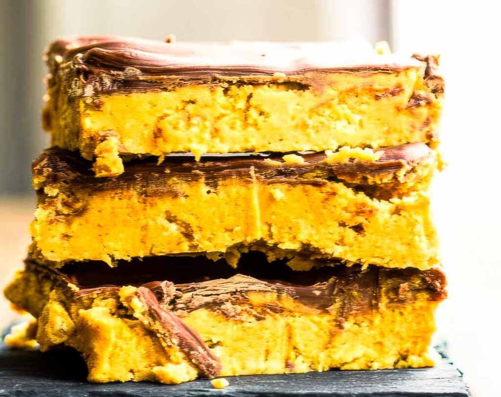 a closeup of a stack of three no-bake peanut butter bars on a black plate