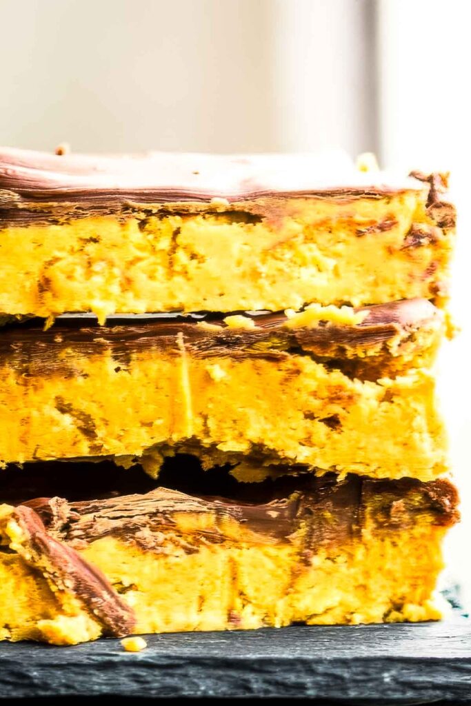 an extreme closeup of stack of three no-bake peanut butter bars on a black plate