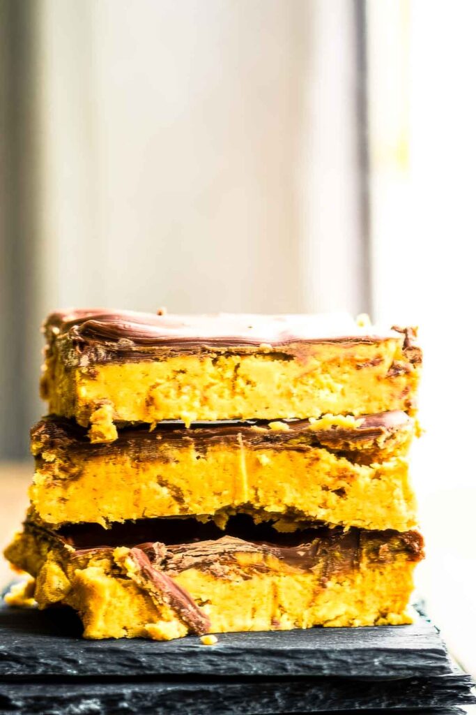 a stack of three no-bake peanut butter bars on a black plate