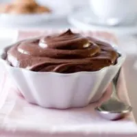 homemade chocolate pudding in a white, scalloped dish on a pink napkin