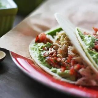 crab tacos with salsa and avocado sauce on a red plate