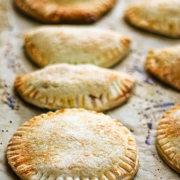 a closeup of peach hand pies just out of the oven, on a parchment lined sheet pan