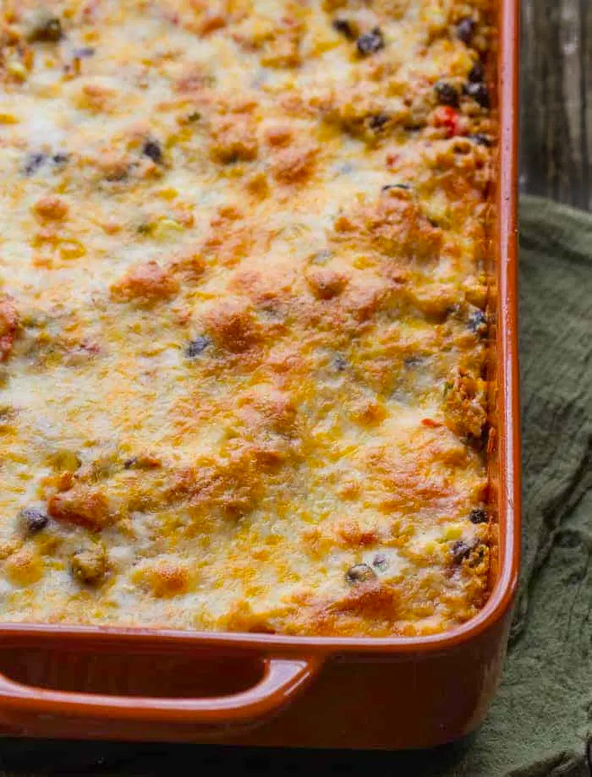 Healthy Mexican Quinoa Casserole a Mexican quinoa casserole just out of the oven on a rustic wood table