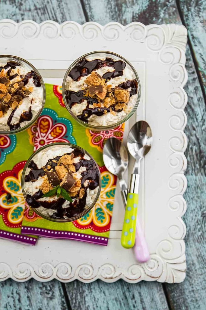 The Best No Bake Butterfinger Pie – Just 10 Minutes Prep! three servings of no bake butterfinger pie on a colorful napkin with two spoons