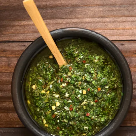 Chimichurri sauce made of parsley, garlic, oregano, hot pepper, olive oil, vinegar, served in rustic bowl,