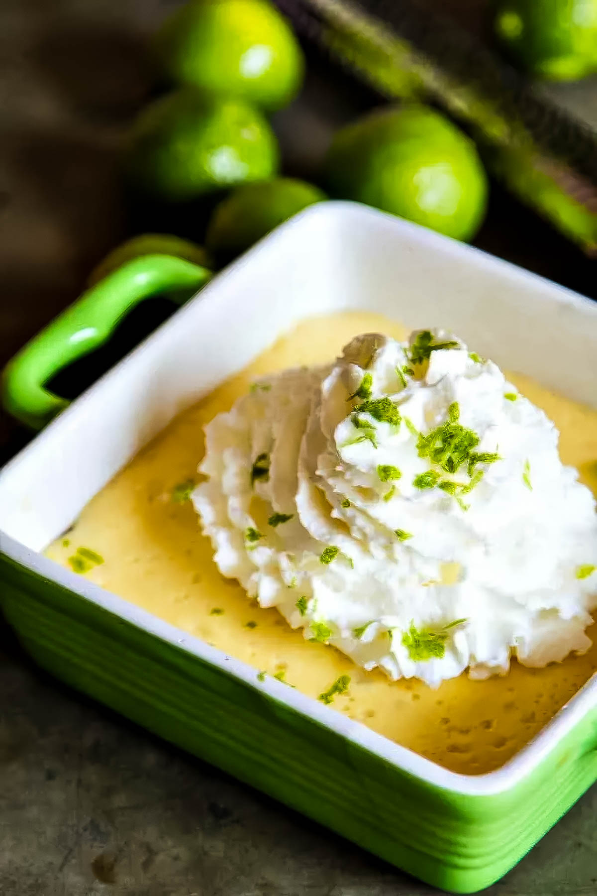 an individual key lime pie made with a granola crust, topped with whipped cream and fresh lime zest