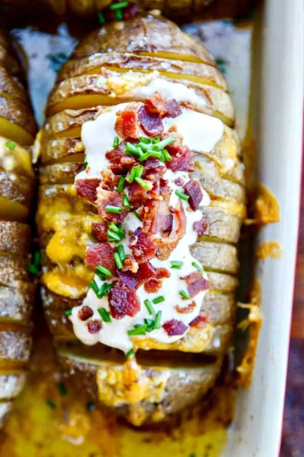 Gorgeous and easy baked potatoes loaded with chipotle sour cream, crispy bacon and chives! Hasselback potatoes are so easy to make with a buttery, soft inside, gooey cheese and all the fixins!