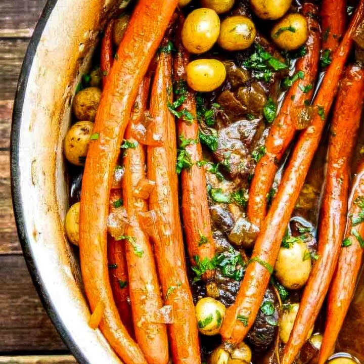 Overhead view of a Dutch oven filled with tender chuck roast, whole carrots, and baby potatoes