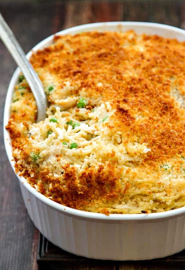turkey tetrazzini with parmesan panko topping in a white casserole dish and an antique silver spoon