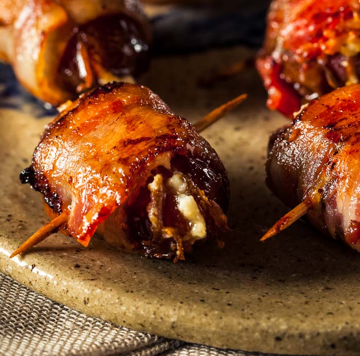 Bacon-wrapped dates with blue cheese on a speckled brown plate