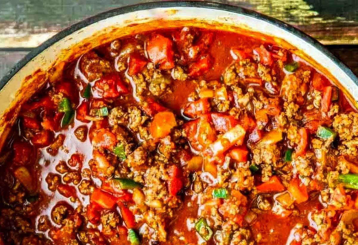 Thick and Beefy Beanless Chili Recipe an overhead shot of a big pot of beanless chili on a wood table