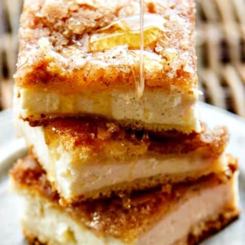 a stack of sopapilla cheesecake bars drizzled with honey
