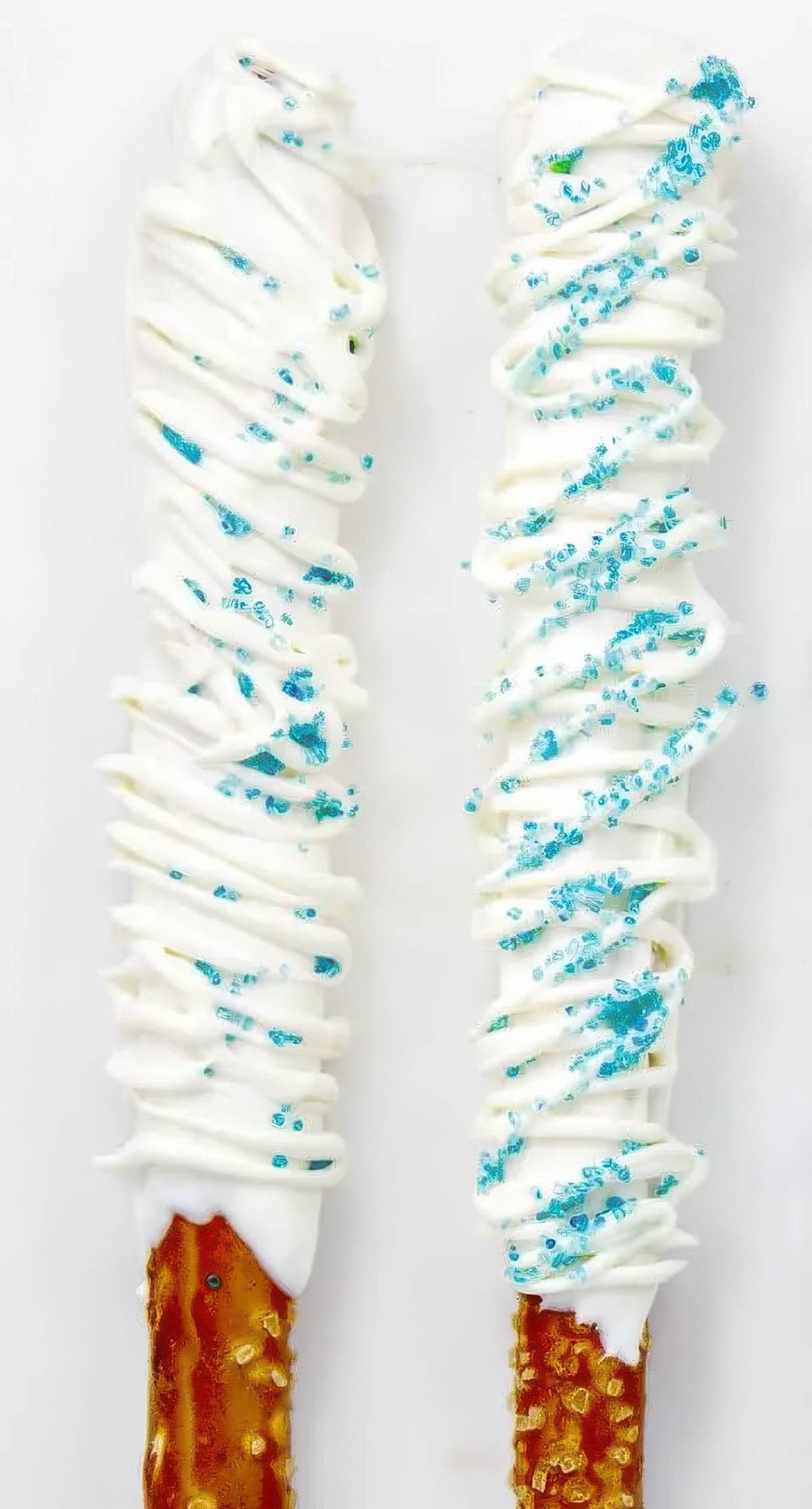 Two chocolate covered pretzel rods decorated with white chocolate and blue sprinkles for a "Frozen" theme