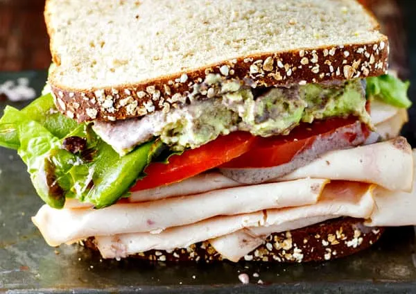 A healthy turkey sandwich recipe! Piled high with turkey, lettuce, tomato, roasted anaheim peppers and a creamy black bean spread!