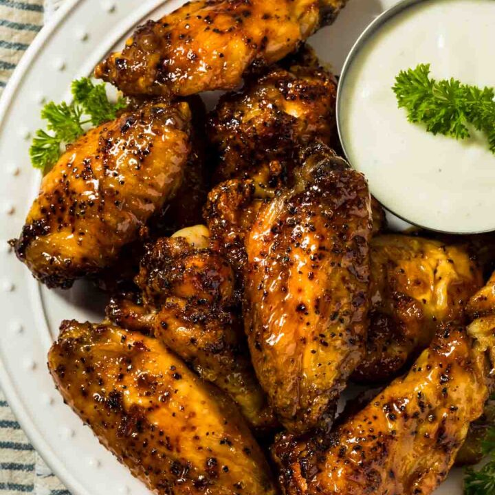 a platter of hot honey chicken wings with a small dish of ranch dressing for dipping