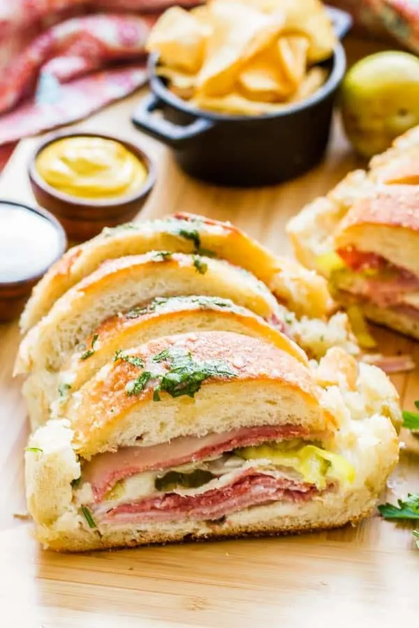 Why make individual sandwiches when you can make one BIG one that feeds everyone? This Garlic Bread Sandwich Loaf recipe has loads of goodies layered inside, then it's doused with a combination of melted butter, garlic, parmesan and parsley. It is AMAZING!! AND EASY!!