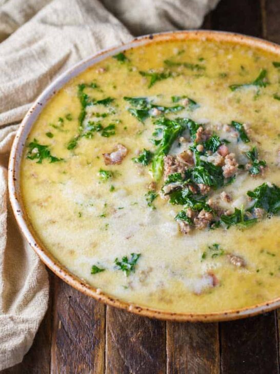 Instant Pot Zuppa Toscana Soup in a large bowl, sitting on a wood table with a beige towel.