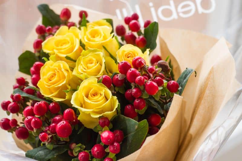 debi lilly floral bouquet with yellow roses and red berries