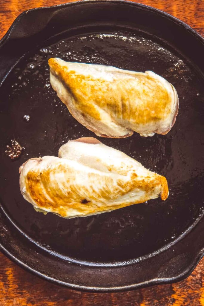 Air Chilled Chicken: Why It’s Better + A Recipe two air chilled chicken breasts being seared in a cast iron skillet