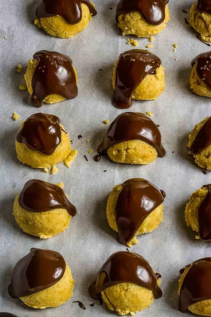 a closeup of keto cookie dough bites on parchment paper with a drizzle of chocolate