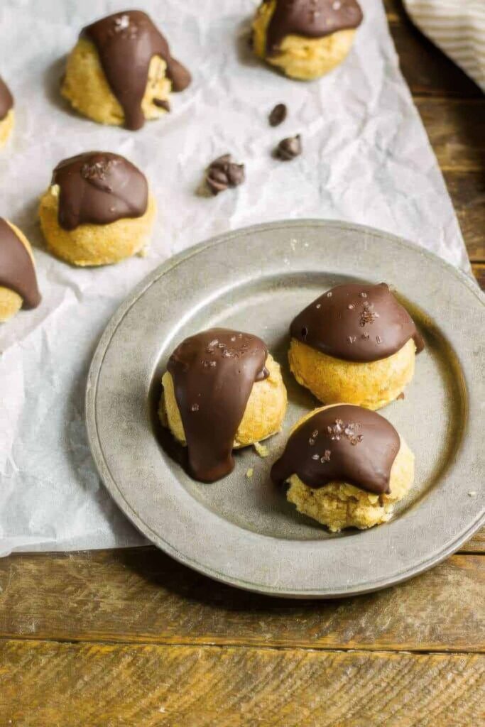 three keto cookie dough bites on a silver plate with a drizzle of chocolate