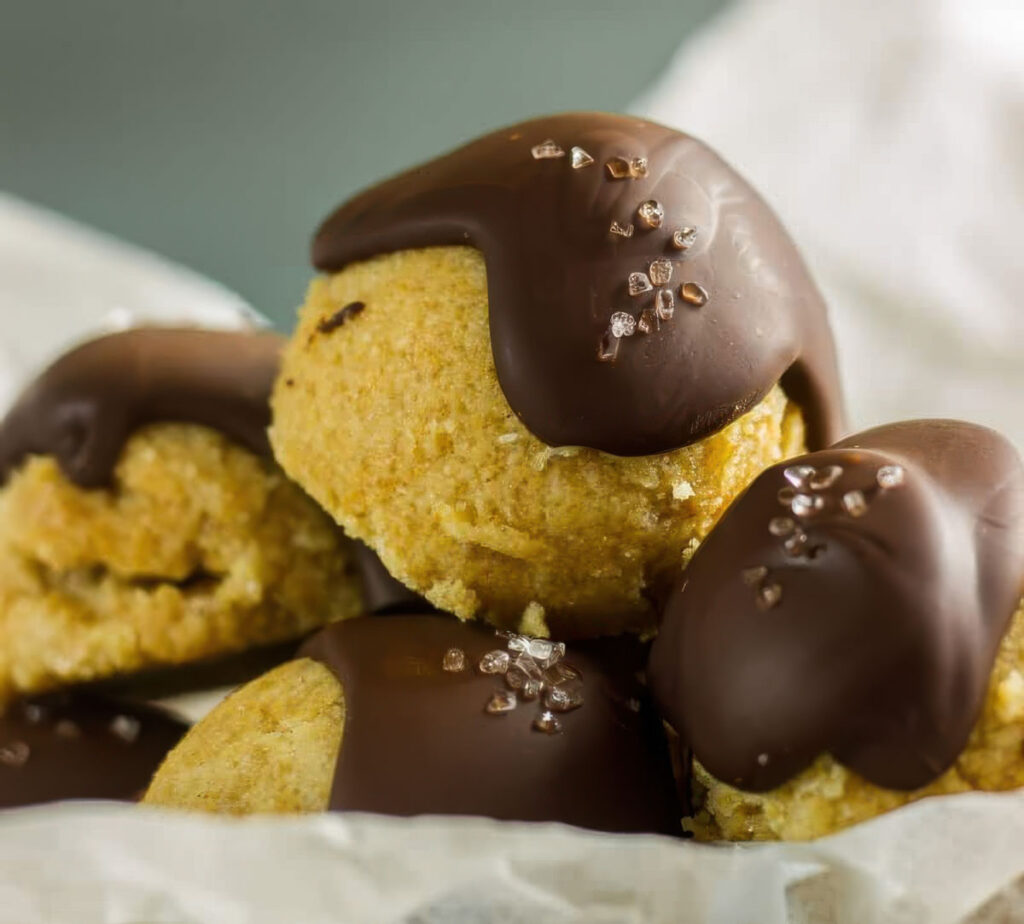 a pile of keto cookie dough bites with a drizzle of chocolate and flaky sea salt