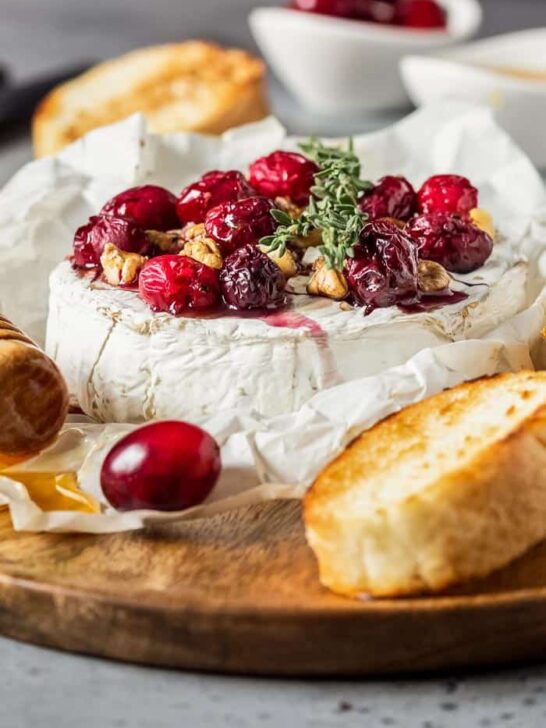 Baked Camembert with Cranberries and Walnuts on a wooden board with bread