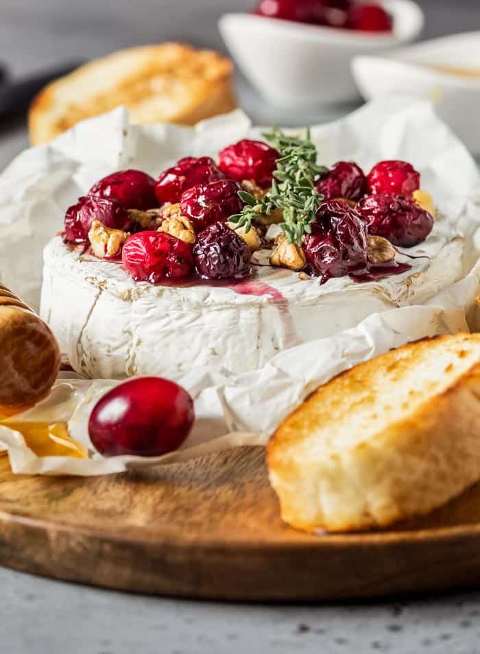 Baked Camembert with Cranberries and Walnuts on a wooden board with bread