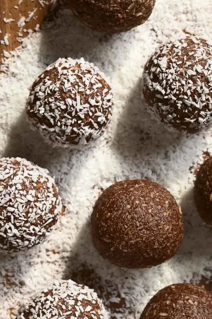 Coconut rum balls being rolled and coated in coconut