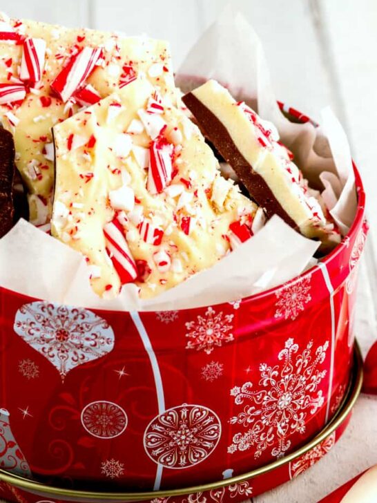Homemade chocolate peppermint bark in decorative tin with candy cane