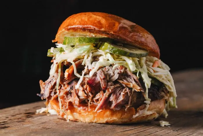 A photo of a pulled pork sandwich with coleslaw and pickles using Instant Pot pulled pork
