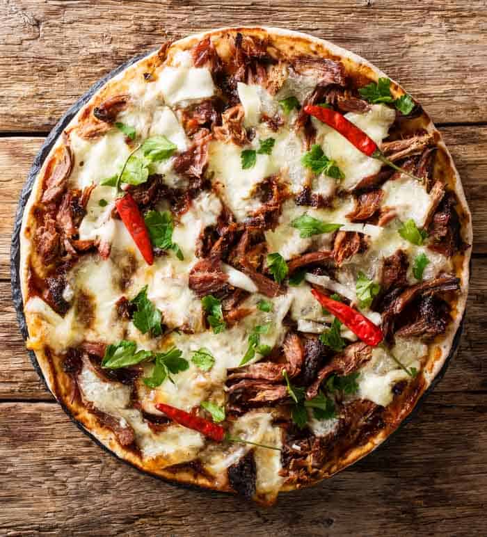 Pulled pork pizza on a wood table