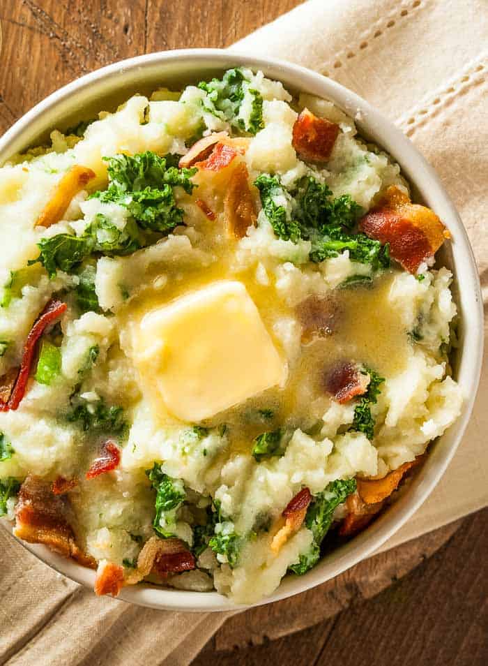 A bowl of colcannon on a tan napkin over a wood table
