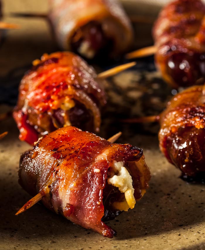 Bacon-wrapped dates with blue cheese on a brown plate