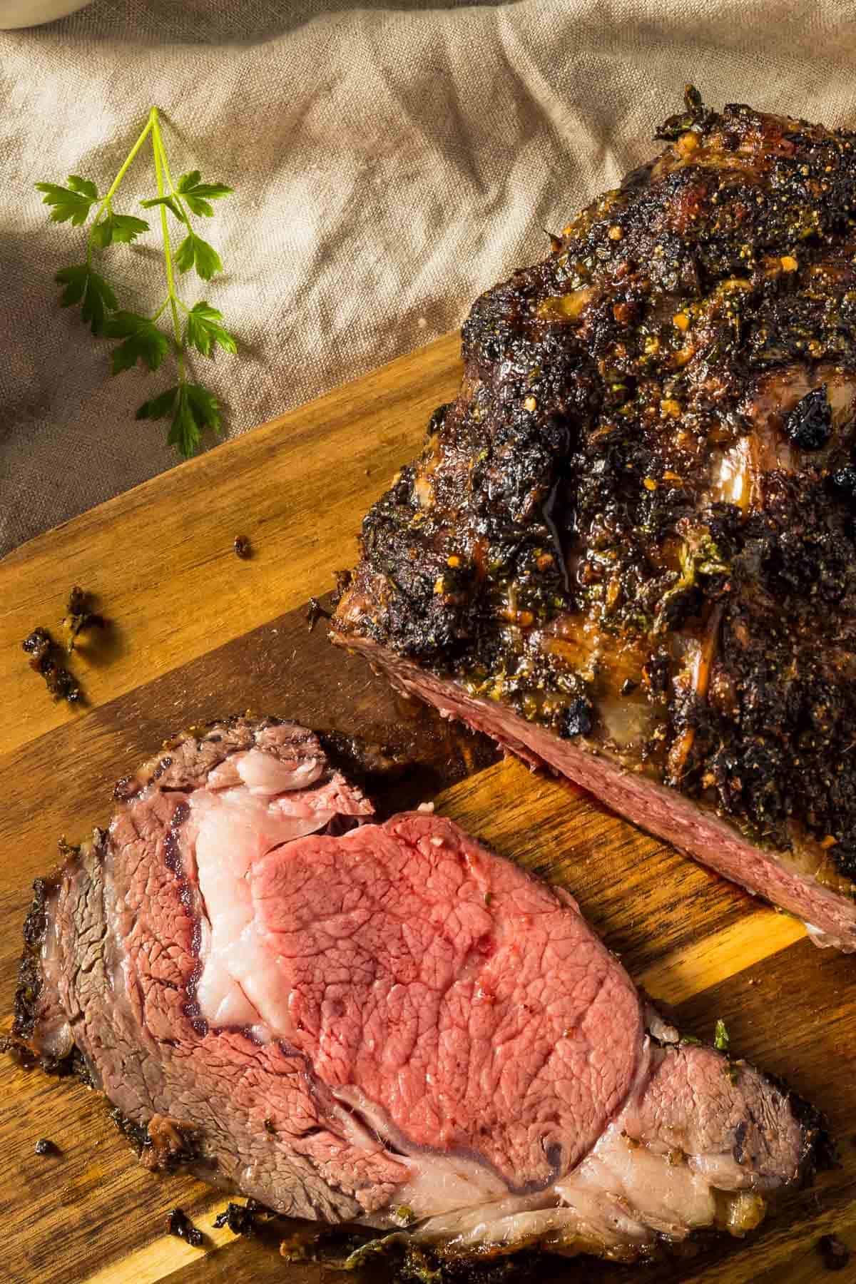 a closeup of a boneless prime rib just out of the oven resting on a wooden cutting board