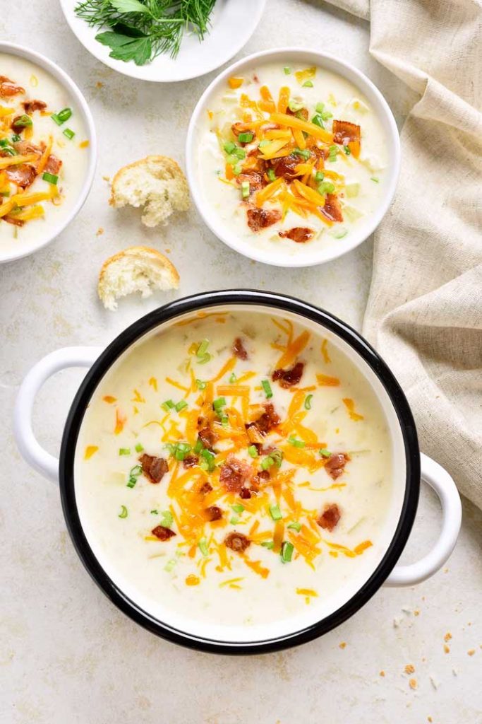 a pot of loaded potato soup with two filled bowls