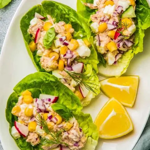 a plate of tuna salad lettuce wraps with lemon wedges