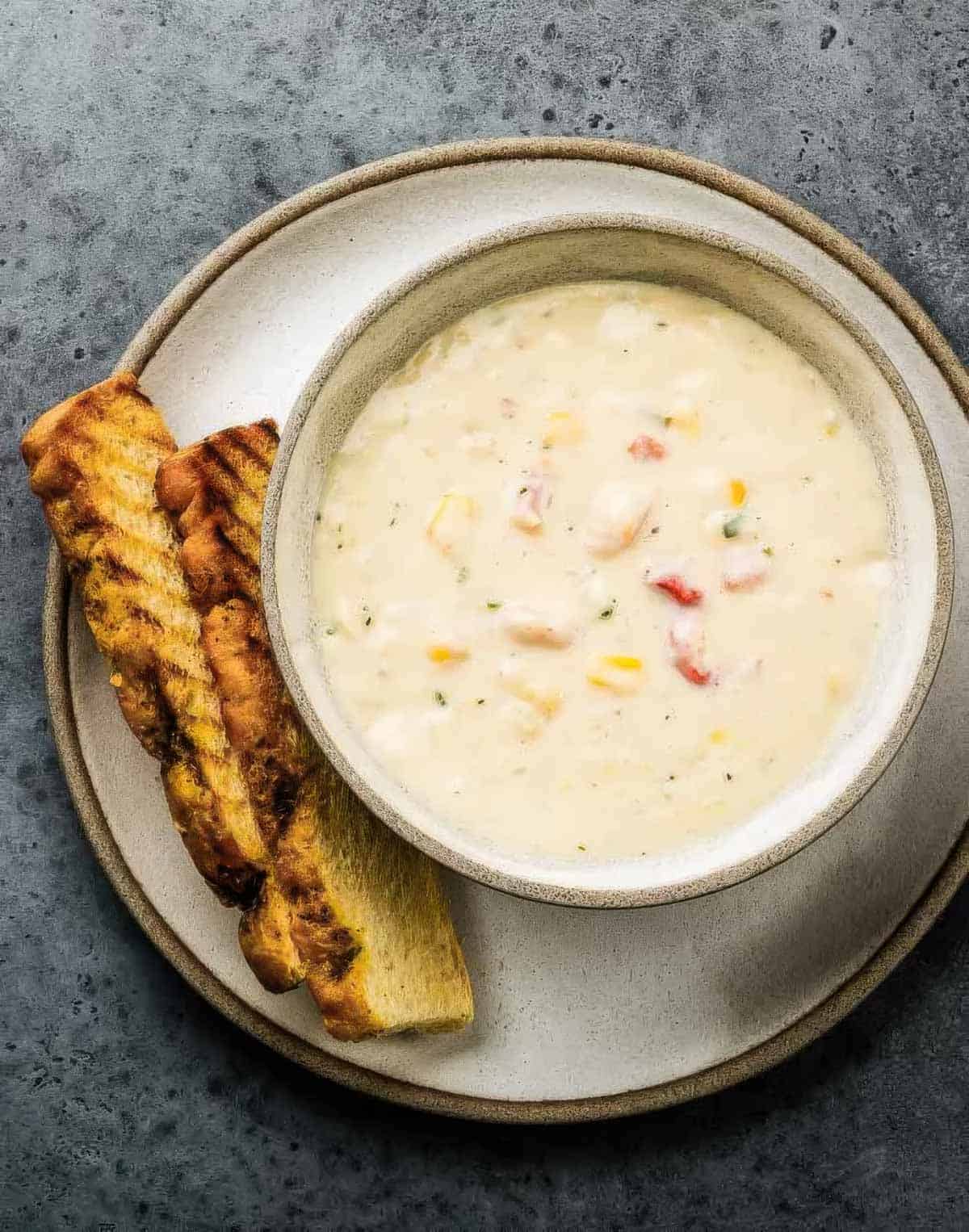 a hearty bowl of seafood chowder with two slices of grilled bread