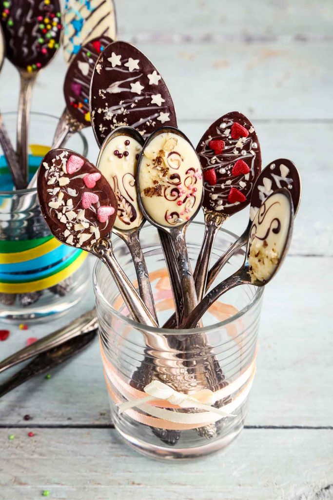 chocolate spoons with sprinkles, nuts, and hearts, set in a glass tied with ribbon