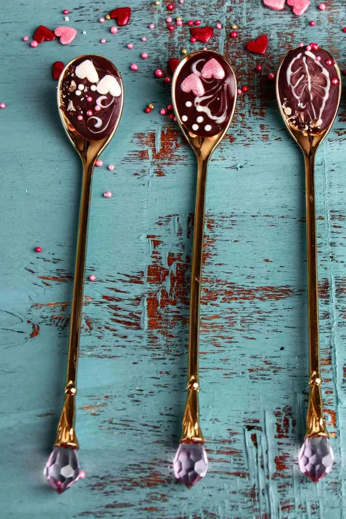 a set of three chocolate spoons with long handles on a teal tabletop