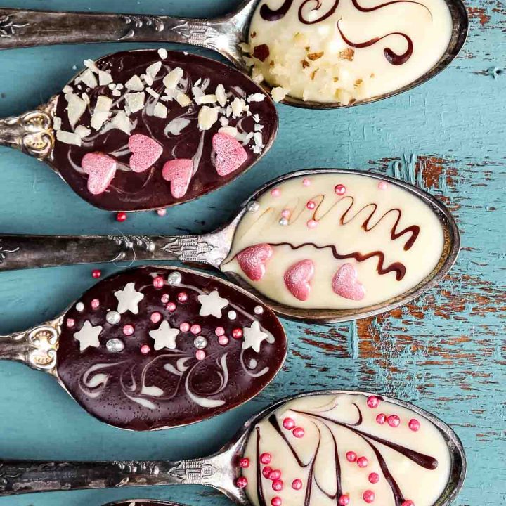 a set of seven chocolate spoons with sprinkles, nuts, and hearts