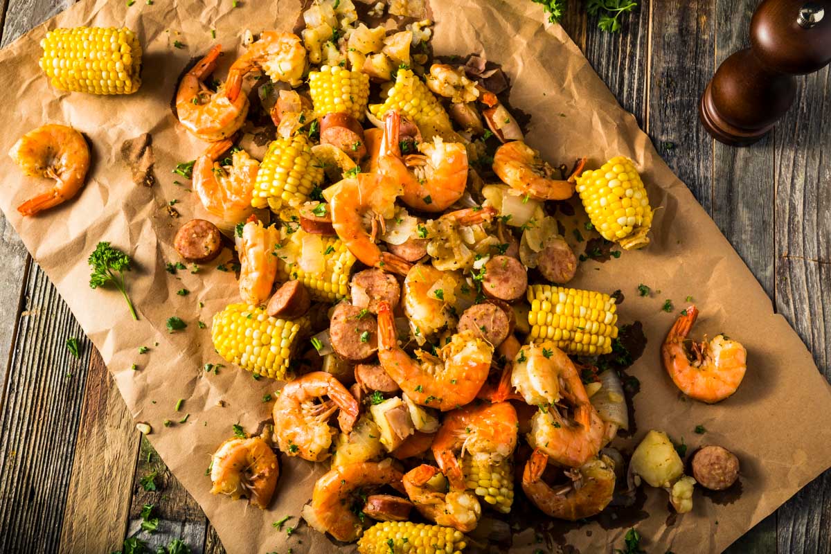 Shrimp and Sausage Boil (One-Pot, 30 minutes) an overhead shot of a fully cooked shrimp and sausage boil with corn and potatoes on a large sheet of parchment paper