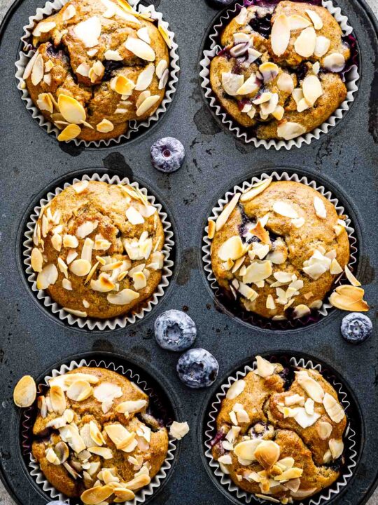 a closeup of banana blueberry oatmeal muffins in a muffin pan just out of the oven