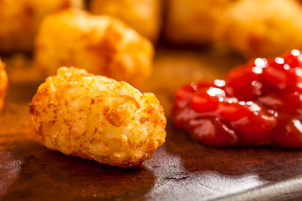 air fryer tater tots on a wooden board with some ketchup