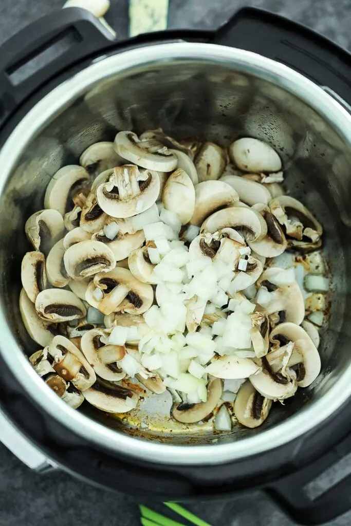 Adding sliced mushrooms and onions to the Instant Pot for beef stroganoff