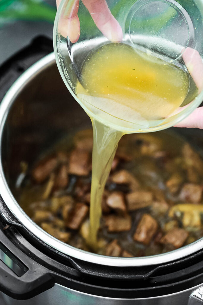 adding chicken broth to an instant pot for beef stroganoff