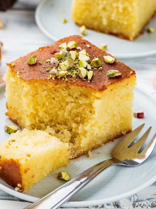 Closeup of sliced Revani Turkish Cake on a Plate with Pistachio Garnish