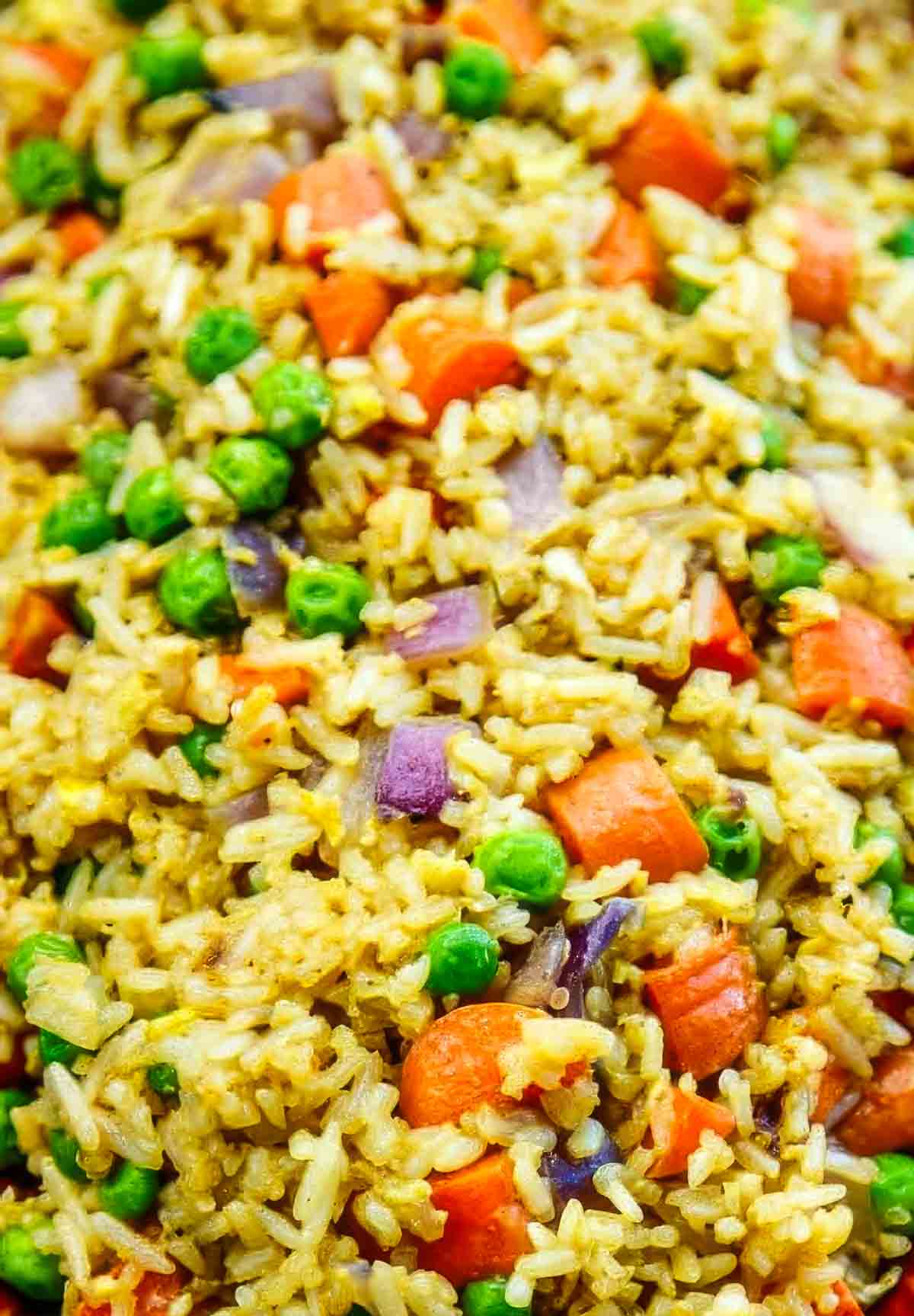 an extreme closeup of easy fried rice, with peas, carrots, and onion clearly visible